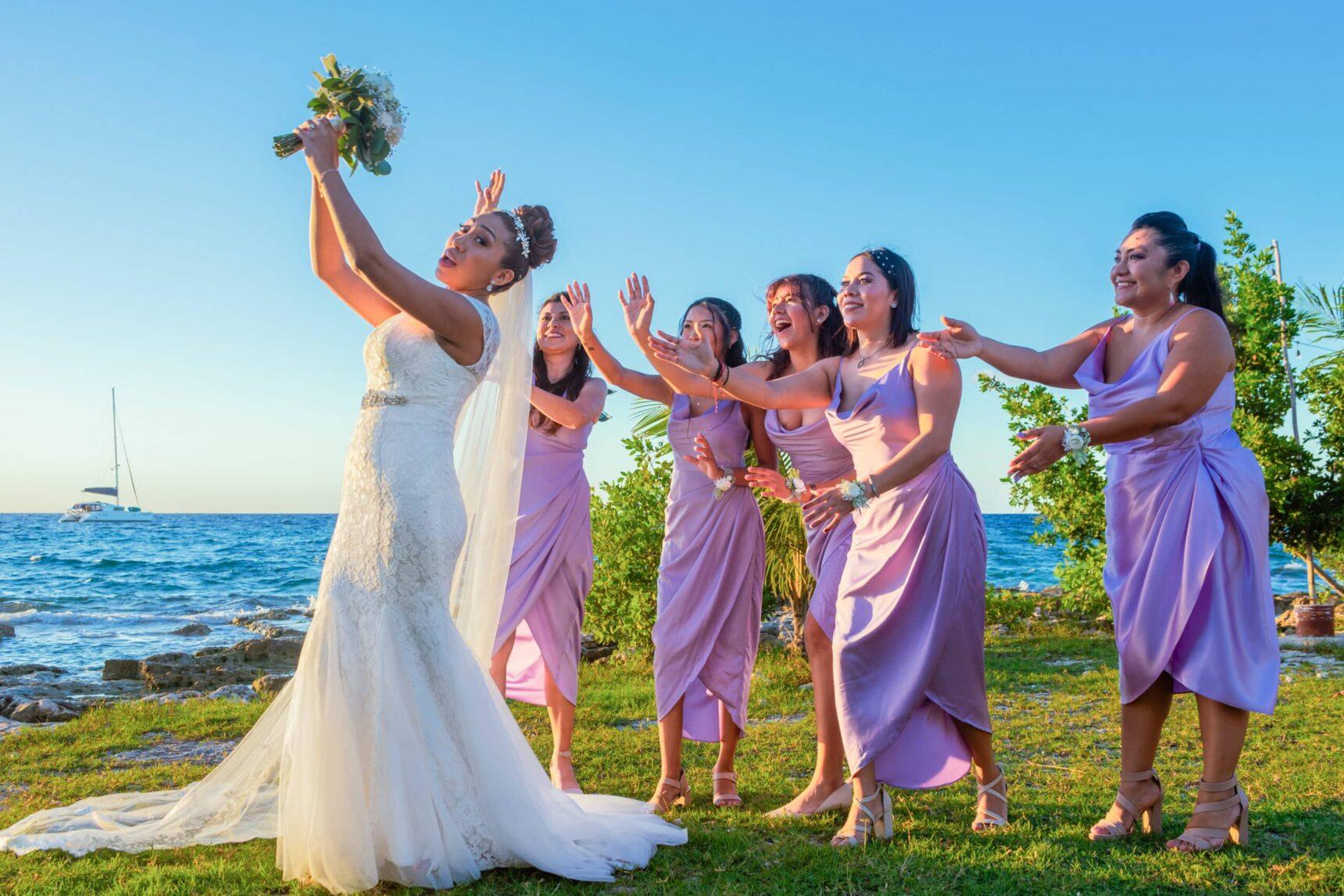 Bridesmaids reaching for the bouquet during a fun beach wedding ceremony in Cozumel – destination wedding photography