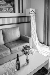 Black and white photo of a wedding dress hanging in a quiet bridal suite before a destination wedding in the Riviera Maya