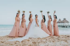 Bride and groom laughing with their wedding party during a fun candid moment in Cancun, captured by affordable wedding photographers