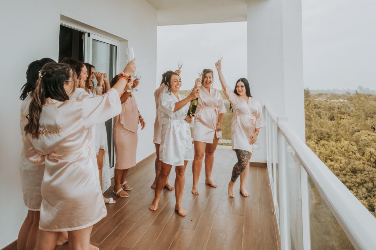 Damas de honor celebrando en el balcón del hotel antes de la boda en la Riviera Maya