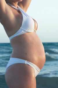 Pregnant woman holding her belly during a maternity photo session in the jungle of Tulum, surrounded by tropical nature
