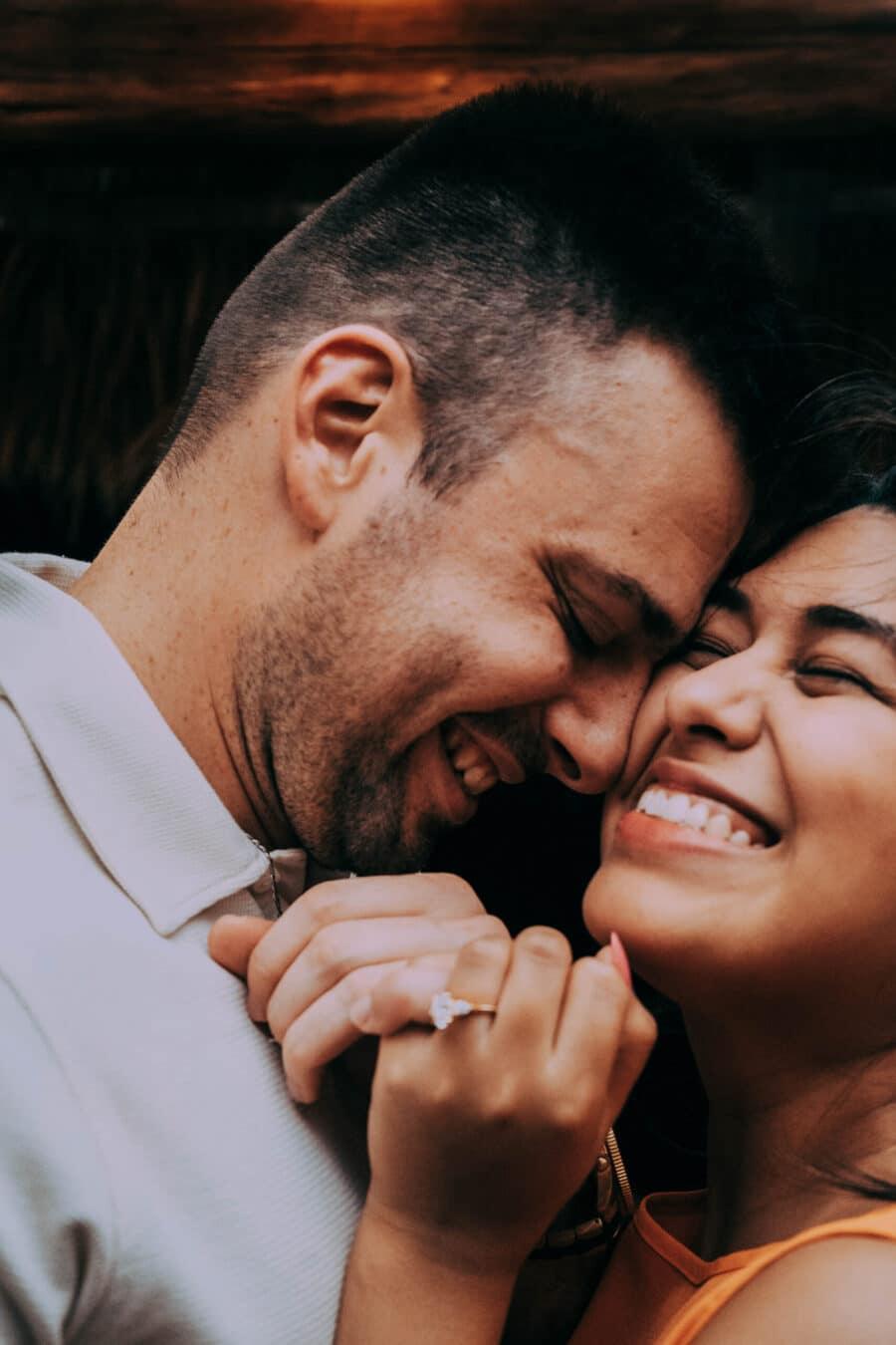 Couple laughing and showing engagement ring after proposal