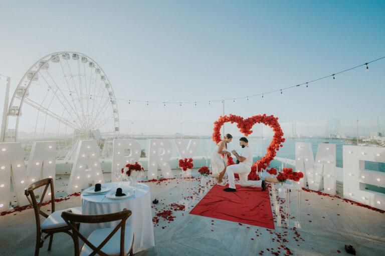 Marriage proposal in front of the Ferris wheel in Cancún with stunning romantic decor at sunset