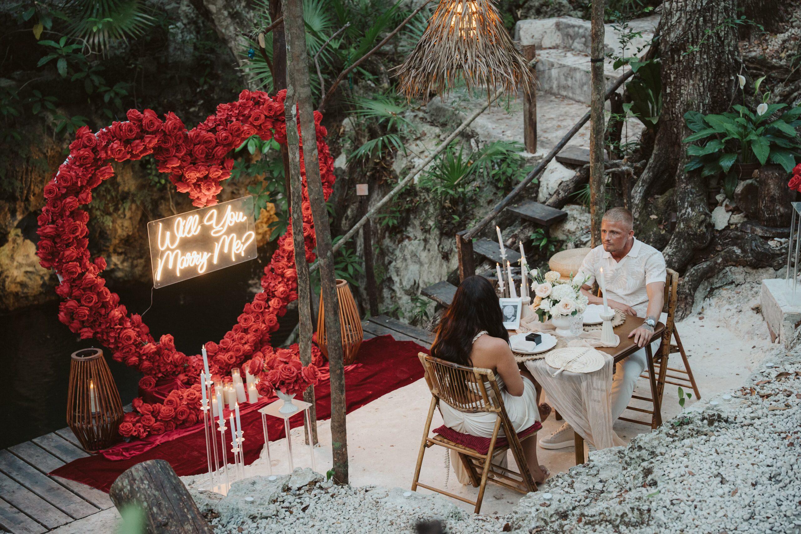 Couple having a romantic dinner during a beachfront marriage proposal with candles and elegant decor